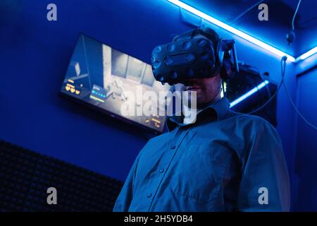 Man in VR glasses are prepared for gaming and ready to play in virtual reality game club. Modern entertainment and leisure concept Stock Photo