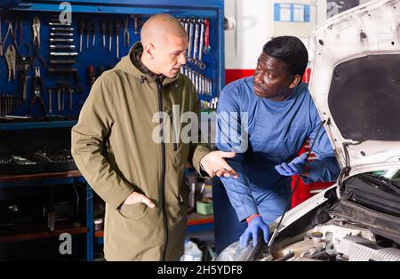 Owner of car explains the problem with car engine to mechanic of the car service Stock Photo