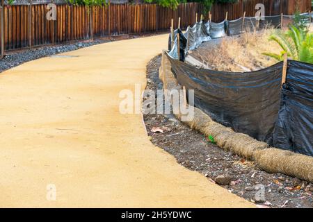 Straw wattle and plastic fence are placed along the waterway to reduce soil erosion, debris runoff and retain sediment during pedestrian trail constru Stock Photo