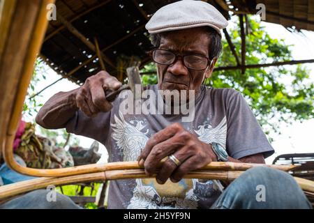 July 2017. Arenesto Deguen making an infant's walker from ratan. Local handicrafts like this add value over simply harvesting the ratan, but are difficult to market and capitalize on without a better distribution system. Aborlan, Barangay Sagpangan, Palawan, Philippines. Stock Photo