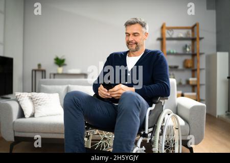 Older Man With Disability Using Smartphone Or Mobile Phone Stock Photo