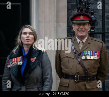 Downing Street, London, UK. 11 November 2021. Alice Wingate, the grand-daughter of Major General Orde Wingate (the Chindits) arrives in Downing Street for a photograph at the front door after attending the Remembrance Day Parade in Whitehall. She wears her grandfathers impressive medals including the DSO & Two Bars. She is accompanied by an officer of the Princess of Wales’s Royal Regiment, the Army Tigers. Credit: Malcolm Park/Alamy Stock Photo