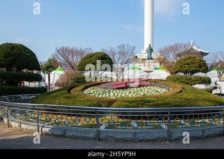 Busan, South Korea - November 28, 2015: Floral clock on background statue of Yi Sun-sin and Busan Tower. Stock Photo