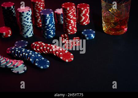 Poker chips and wine glass of cognac on dark table. Gambling Stock Photo