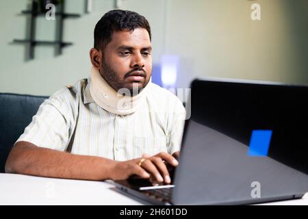 fat man with neck brace working on laptop due to neck pain during work from home - concept of overworking and unhealthy food habits during coronavirus Stock Photo