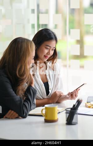 Happy female colleagues are discussing and sharing ideas for their project in modern office. Business concept Stock Photo