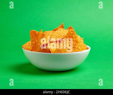 Bowl of nachos corn chips on green background Stock Photo