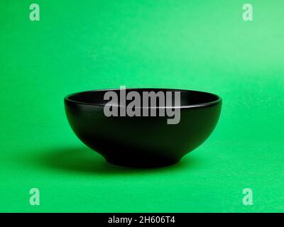 Empty black ceramic bowl on green background Stock Photo