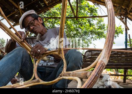 July 2017. Arenesto Deguen making an infant's walker from ratan. Local handicrafts like this add value over simply harvesting the ratan, but are difficult to market and capitalize on without a better distribution system. Aborlan, Barangay Sagpangan, Palawan, Philippines. Stock Photo