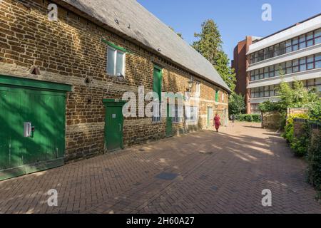 Street scene, Wellingborough, Northamptonshire, UK; on the left the 15th century Tithe Barn, on the right a modern office block. Stock Photo
