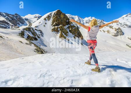 Woman with open arms enjoing the panorama of Diavolezza col in Switzerland at sunset. Piz Bernina skyline view with Morteratsch glacier in Grisons Stock Photo