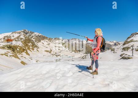 girl walking at sunset with trekking poles on top of Diavolezza col. Mount Pers and Piz Trovat of Switzerland in Graubunden canton. Stock Photo