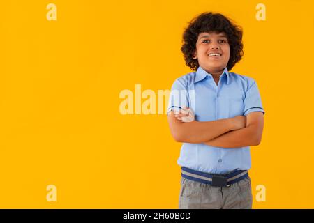 PORTRAIT OF A HAPPY BOY STANDING IN FRONT OF CAMERA WEARING SCHOOL UNIFORM Stock Photo