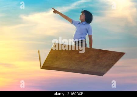 portrait of a boy pointing away while flying on book Stock Photo