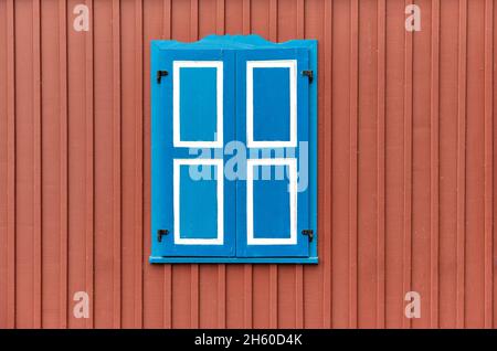 Colorful painted building wall with closed wooden shutters on  window, minimalist architecture background Stock Photo