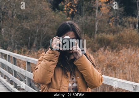 Portrait of young woman taking photos of beautiful autumn nature with a vintage film camera Stock Photo