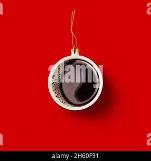 Christmas bauble decoration made of cup of coffee on red background. Minimal concept for Christmas or New Year. Stock Photo