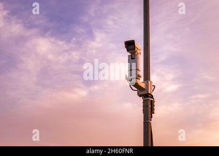 Speed camera on the pole against the backdrop of the sunset sky. Stock Photo