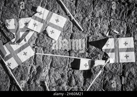 Many teared apart georgian flags on pavement. Crisis in caucasus concept. B&w background banner Stock Photo