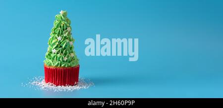Snowing on Christmas tree cupcakes isolated on blue background Stock Photo