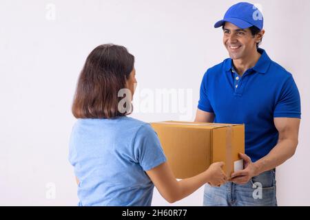 Delivery man in blue t-shirt giving parcel to a woman Stock Photo