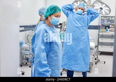 Group of doctors and operating room nurses stand tired and exhausted in the operating room of the clinic Stock Photo