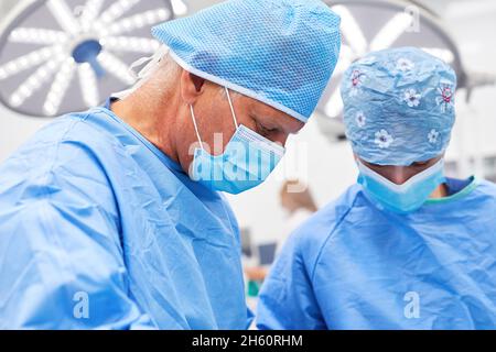 Surgeons team with face mask works concentrated during the operation in trauma surgery Stock Photo