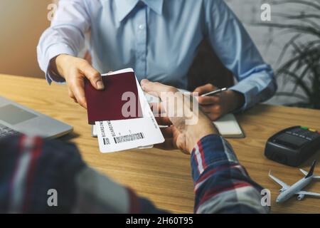 travel agent giving flight tickets and documents to customer in agency office Stock Photo