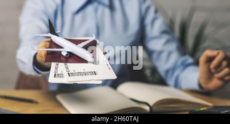 travel agent with flight tickets and plane model in hand at agency office. tourism service. copy space Stock Photo