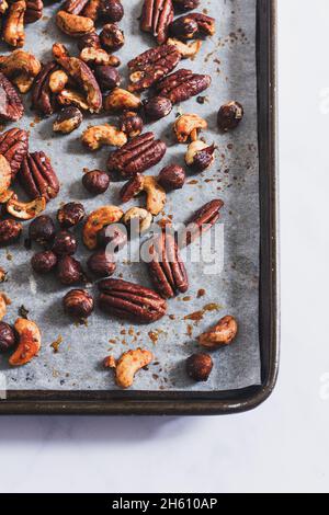 Roasted honey and rosemary mixed nuts (pecan, cashew, hazelnut) on a baking tray. Stock Photo