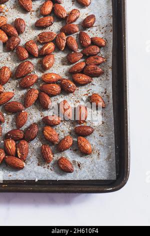 Roasted smoked paprika and sea salt almonds on a baking tray. Stock Photo