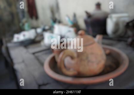 Blurry close up view of broken and dirty tea pot, cups and mugs abandoned on wooden table. Use for background or backdrop. No people. Stock Photo