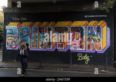 London, UK. 10th November, 2021. A passerby smiles in front of a mural in Brixton by artist Bunny Bread of Create Not Destroy paying homage to hip hop artist Ty's 'Brixton Baby'. The mural was produced for performance poetry organisation Apples and Snakes. Ty, an influential Mercury-Prize nominated rapper who released five albums, was much loved in his local community. He died in May 2020 following complications related to COVID-19. Credit: Mark Kerrison/Alamy Live News Stock Photo