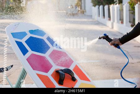 man cleaning with water hose the wing foil board from salt and sand Stock Photo