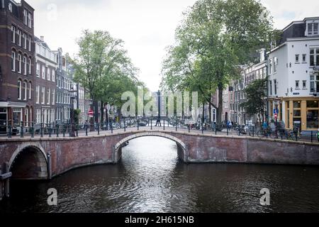 A man walks across a bridge over one of the many canals in the center of Amsterdam, the Netherlands. With 50% of the Netherlands below sea level, it is incredibly vulnerable to climate change driven sea level rise. Stock Photo