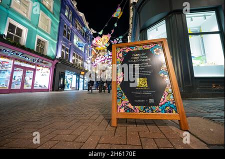 LONDON - NOVEMBER 1, 2021: Sign promoting the Carnaby Street Christmas lights with decorations in the background Stock Photo