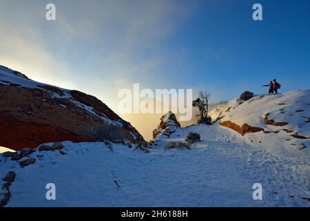 Visitors to Mesa Arch in winter, with fog, Canyonlands National Park, Utah, USA Stock Photo