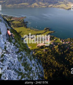 Via ferrata in the Alps. Man sits on a rock face. Lake in Autria Stock Photo