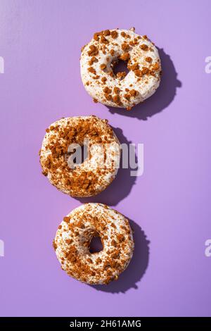 Sweet glazed donut with sprinkles on violet background. Top view. Stock Photo