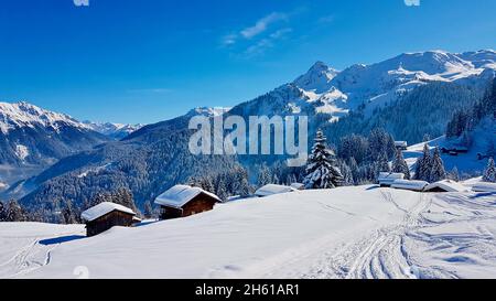 Traditional wooden mountain huts on a sunny winter day. Vorarlberg, Austria. Stock Photo