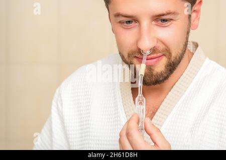 Young caucasian man receiving nasal inhalation Maholda with essential oil in the nose at a hospital Stock Photo