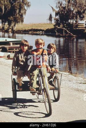 Children of fishermen on homemade tricycle; Bayou Gauche  ca. February 1973 Stock Photo