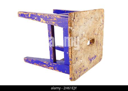 Old used wooden stool with peeling dark blue paint laid on its side. Loft style chair isolated on a white background. Stock Photo
