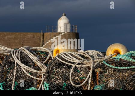 FINDOCHTY VILLAGE MORAY COAST SCOTLAND BLACK FISHING CREELS AND YELLOW FLOATS ON THE HARBOUR WALL Stock Photo