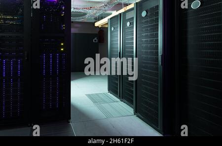 Data center with multiple rows of fully operational server racks Stock Photo