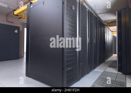 Data center with multiple rows of fully operational server racks Stock Photo