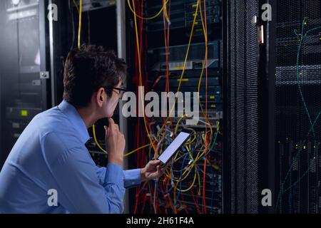 Thoughtful asian male engineer using digital tablet and inspecting computer server in server room Stock Photo