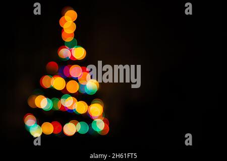Christmas tree multicolored bokeh on dark background. Defocused multi colored lights. New Year, Christmas background, abstract texture. Copy space Stock Photo