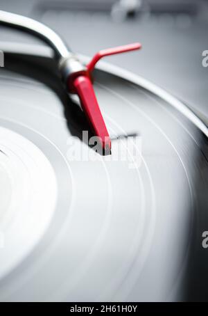 Retro turntable player in close up.Red needle cartrdige on black analog vinyl disc with music.Vertical shot of turn table device playing vintage disc Stock Photo