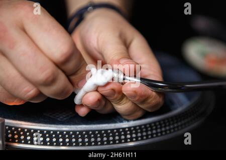 DJ cleans turntables needle and tone arm on retro vinyl record player Stock Photo